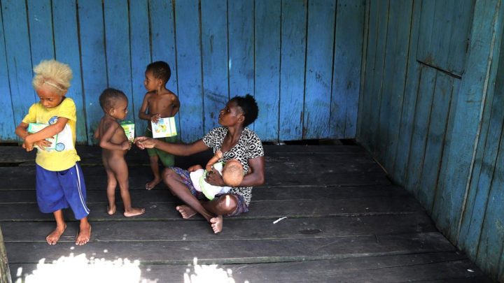 Tiga orang anak memegang bungkusan makanan tambahan yang dibagikan oleh petugas Puskesmas Agats dalam program pelayanan di rumah-rumah warga di Kampung Ewer, Distrik Bismam, Kabupaten Asmat, Papua, Selasa (16/1). Selain itu mereka juga memberikan vaksin campak.